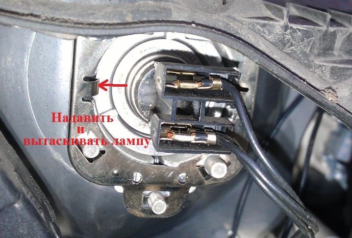 На фотографии показан фиксатор, который держит лампу и на который нужно нажать при ее снятии