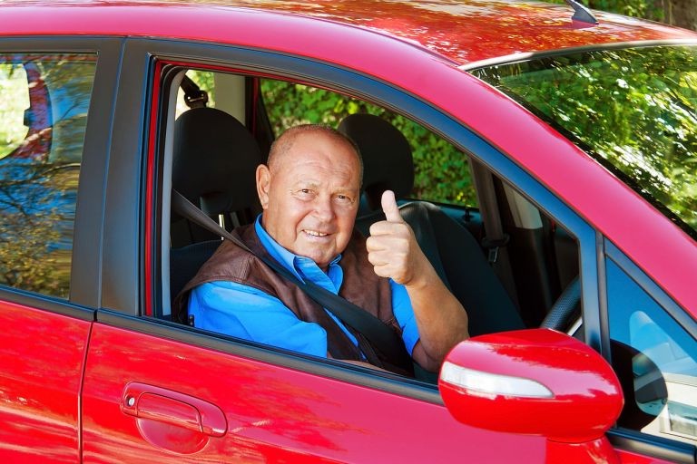 Довольный автолюбитель в отполированном авто Довольный автолюбитель в отполированном авто