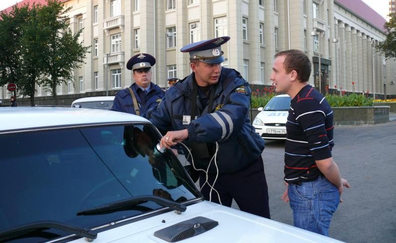 Инспектор измеряет уровень затемнения стекла Инспектор измеряет уровень затемнения стекла